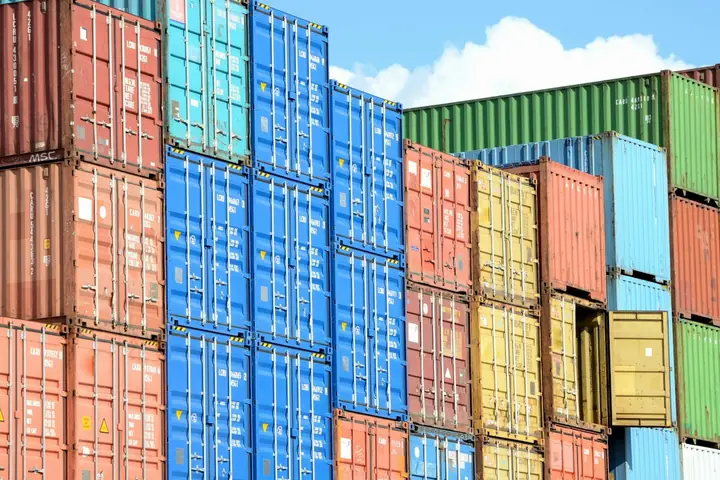 A tall stack of colourful intermodal containers against a blue sky