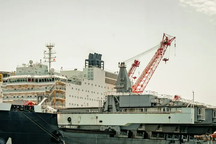 A large offshore construction vessel alongside, with its accommodation block and a red crane