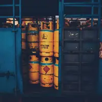Yellow gas cylinders with diamond-shaped hazard labels packed inside a blue steel cage