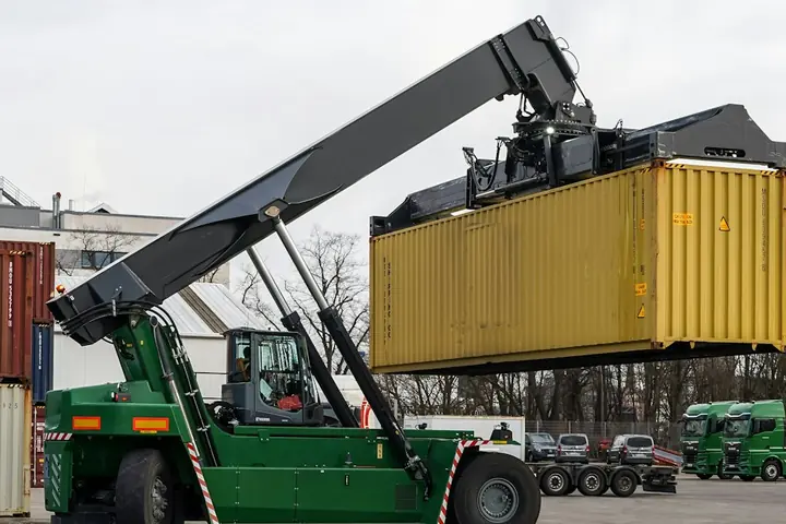 A reach stacker lifting a yellow 40ft container at a port terminal
