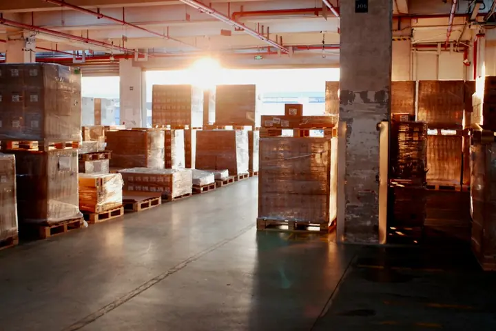 Shrink-wrapped cartons stacked on wooden pallets in a warehouse